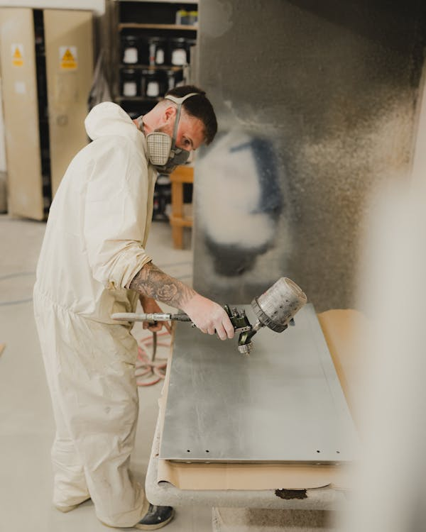 a professional spraying WPU adhesive on a metal slab