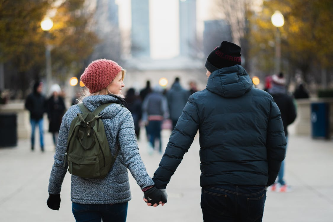 An image of a couple holding hands, wearing jackets