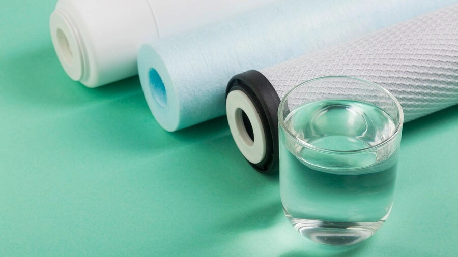 rolls of fabric placed next to a glass of water