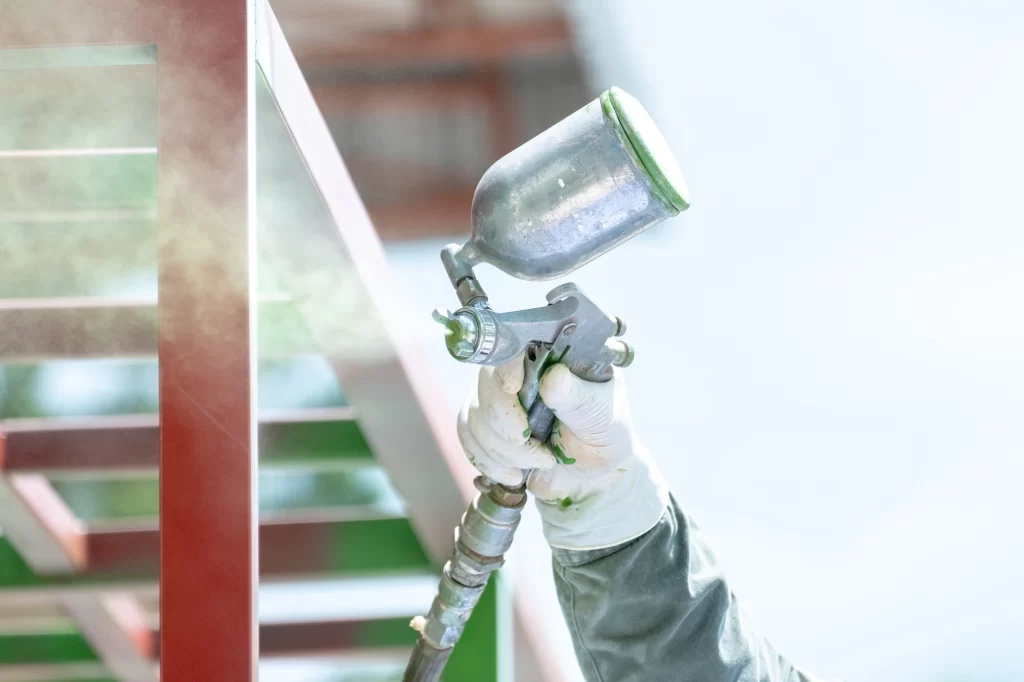 close-up of a spray gun coating a structure before curing