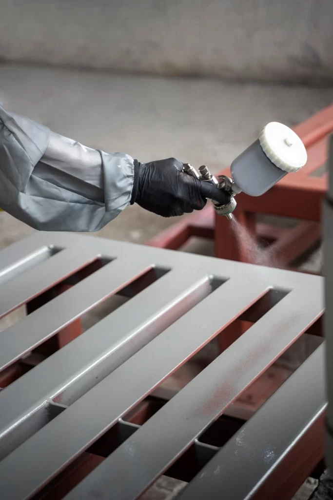close-up of a persons hand using a spray gun for coating
