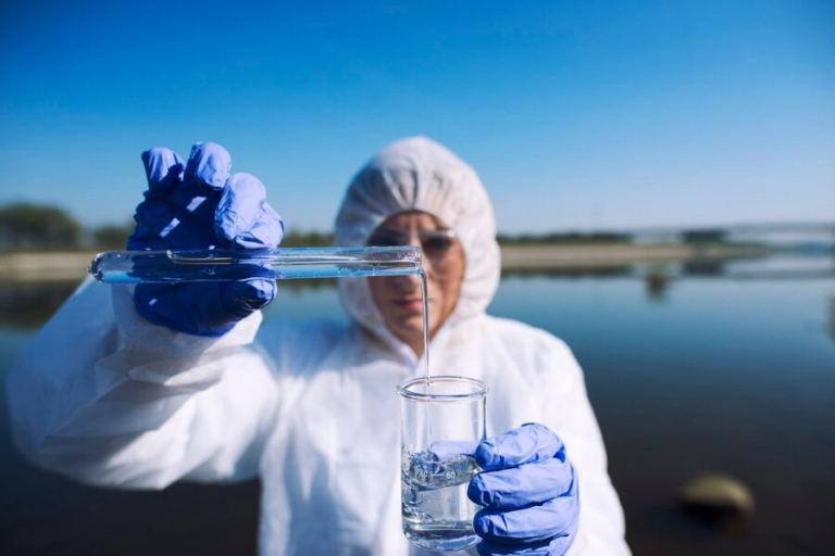 a person using a test tube while wearing a hazmat suit